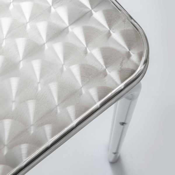 Nahaufnahme einer Tischplatte aus Metall mit kreisförmig geschliffenem Dekor und abgerundeter Kante.