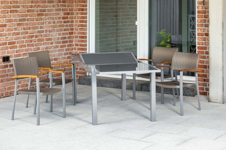Gartenmöbel-Set auf einer Terrasse mit einem Aluminium-Tisch mit Glasplatte und vier Gartenstühlen mit Geflecht und Holzarmlehnen.