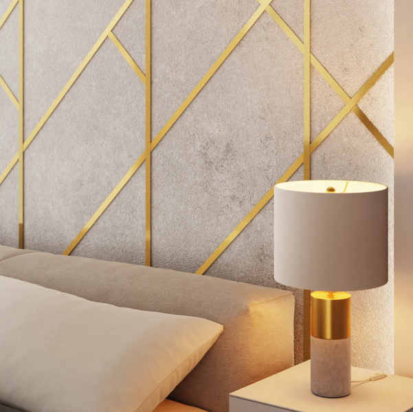 Szene mit Bett, Nachttisch und Lampe vor einer Wand mit goldenen Zierelementen