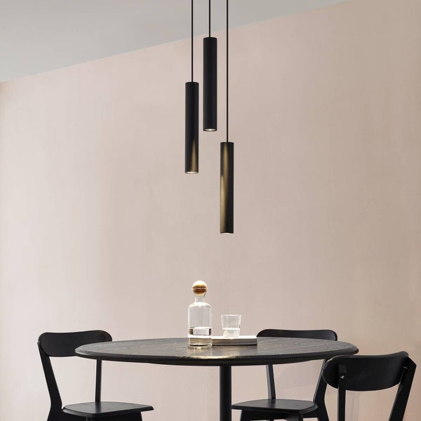 Drei schwarze Pendelleuchten über einem Esstisch