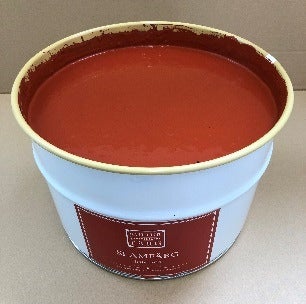Offener Metalleimer gefüllt mit roter Farbe für den Anstrich von schwedischen Holzhäusern.