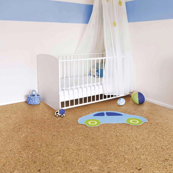 Hell eingerichtetes Kinderzimmer mit Korkboden, weißem Gitterbett mit Betthimmel und einem blauen Kinderteppich in Autoform.