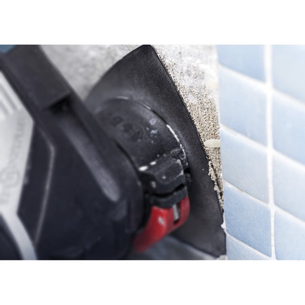 Frau schleift Holz mit einem Exzenterschleifer in einer Werkstatt.