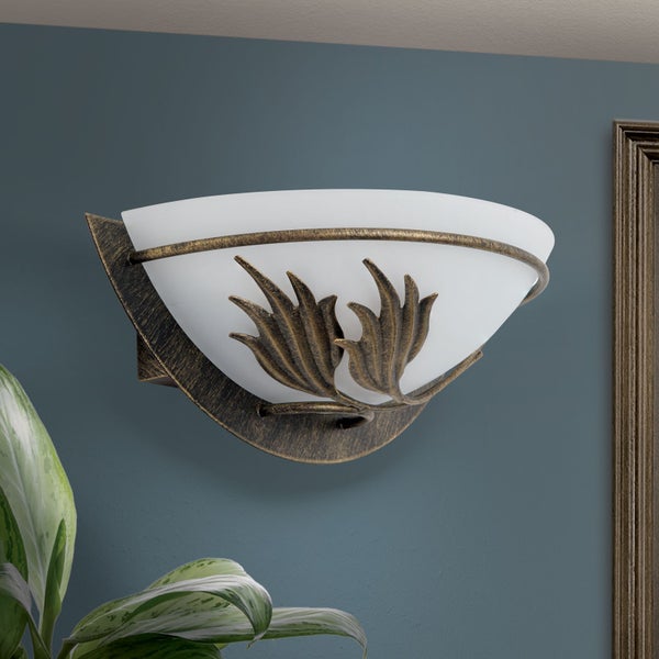 Wandleuchte im Landhausstil aus Metall mit halbrunder Form und ornamentaler Blattverzierung an mattem Glasschirm zur stimmungsvollen Beleuchtung.