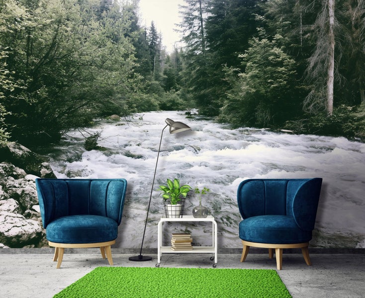 Vlies Fototapete mit Waldfluss Motiv in einem modern eingerichteten Raum mit zwei Sesseln Beistelltisch Stehlampe und Teppich.
