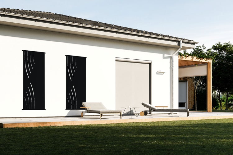 Außenansicht eines modernen Hauses mit Design-Sichtschutzwänden, Liegestühlen und Garten