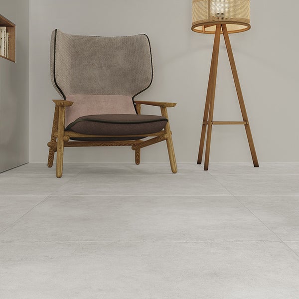 Wohnzimmer mit hellen, großformatigen Fliesen in Betonoptik, modernem Sessel und Stehlampe in einer minimalistischen Einrichtung.