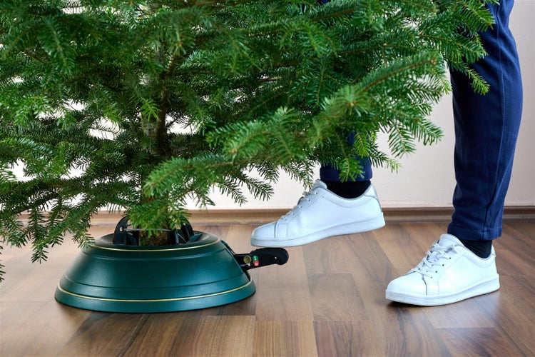 Weihnachtsbaum mit Baumständer und Fußpedal auf Holzboden