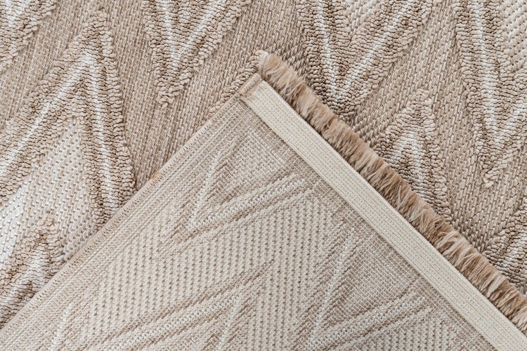 Nahaufnahme eines Teppichs mit geometrischem Muster, die die strukturierte Oberseite und die gewebte Rückseite mit Abschlusskante zeigt.