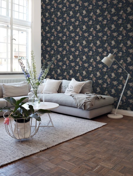 Wohnzimmer mit Sofa, Tisch, Stehlampe und blumiger Tapete