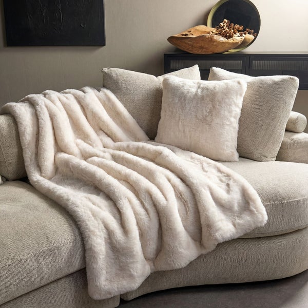 Gemütliches Wohnzimmer mit Sofa, Kissen und Decke