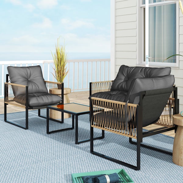 Modernes Gartenmöbel-Set mit zwei Sesseln und einem Tisch auf einer Terrasse mit Meerblick. Graue Polster und schwarze Gestelle.