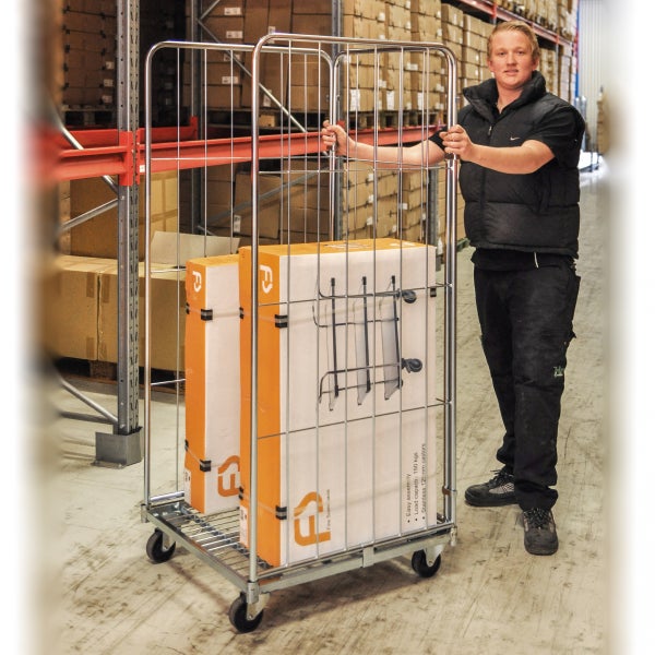 Ein Mann schiebt einen Gitterwagen mit Kartons in einem Lager.