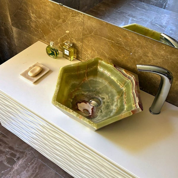 Sechseckiges Aufsatzwaschbecken aus Naturstein auf weißem Waschtisch mit strukturierter Front und Armatur im Badezimmer.