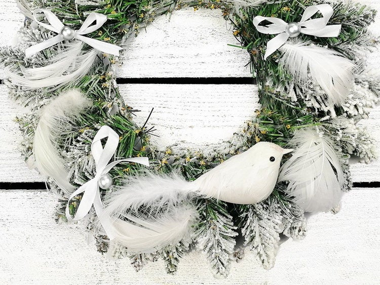 Weihnachtskranz aus künstlichen Tannenzweigen mit Kunstschnee, geschmückt mit Schleifen, Federn und einer Dekovogel-Figur.