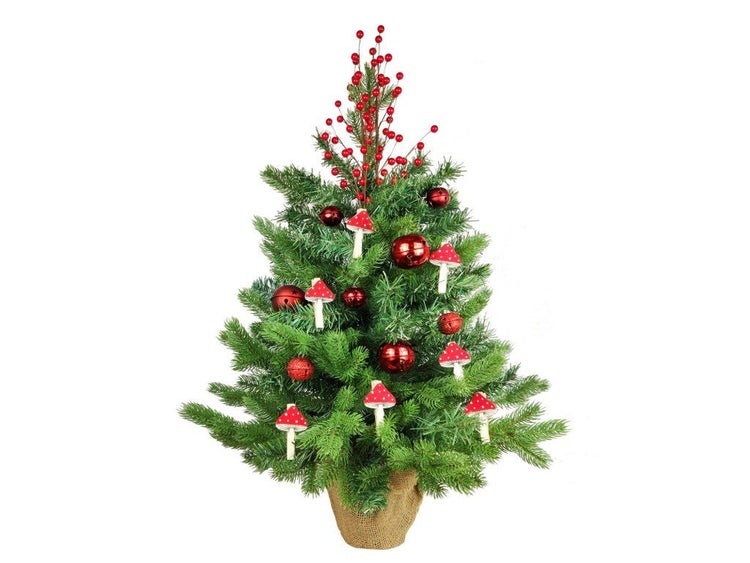 Geschmückter künstlicher Weihnachtsbaum im Jutesack mit Kugeln, Beeren und Fliegenpilz-Anhängern als Weihnachtsdekoration.