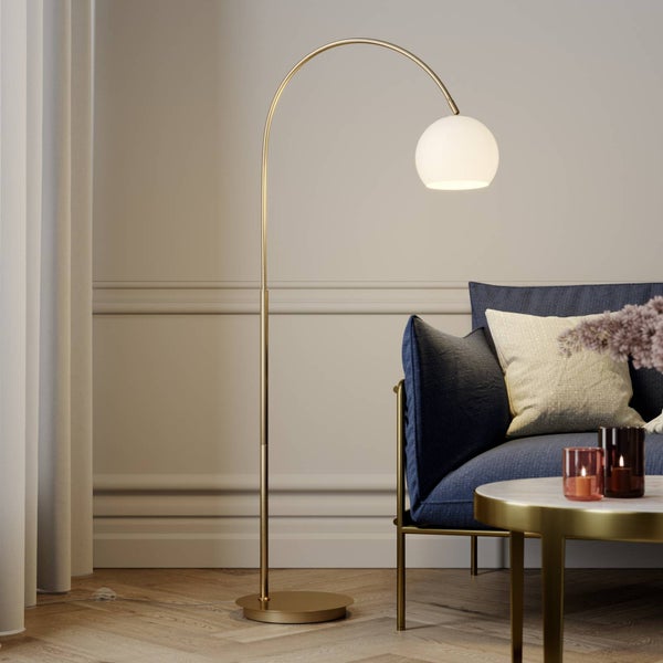 Elegante Stehlampe mit gebogenem, goldenem Gestell und kugelförmigem Lampenschirm neben einem Sofa