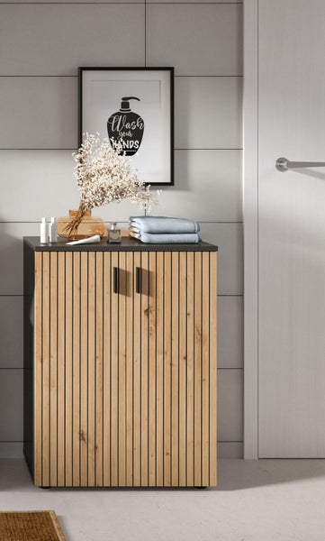 Moderner Badezimmerschrank mit Holzlamellen und schwarzen Griffen in einem Badezimmer mit Vase und Handtüchern.