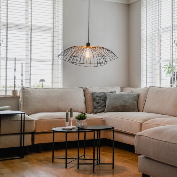 Wohnzimmer mit Ecksofa, Couchtischen und einer Pendelleuchte aus Metall