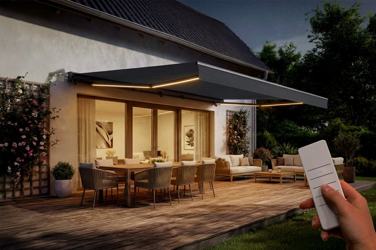 Terrasse mit Markise, Gartenmöbeln und Hand mit Fernbedienung zur Steuerung der Markise.