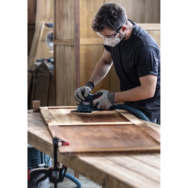 Handwerker schleift Holz mit einem Schwingschleifer der Marke Bosch.