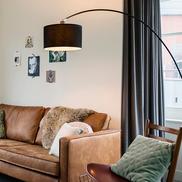 Wohnzimmer mit braunem Sofa, Bogenlampe und Dekoration an der Wand