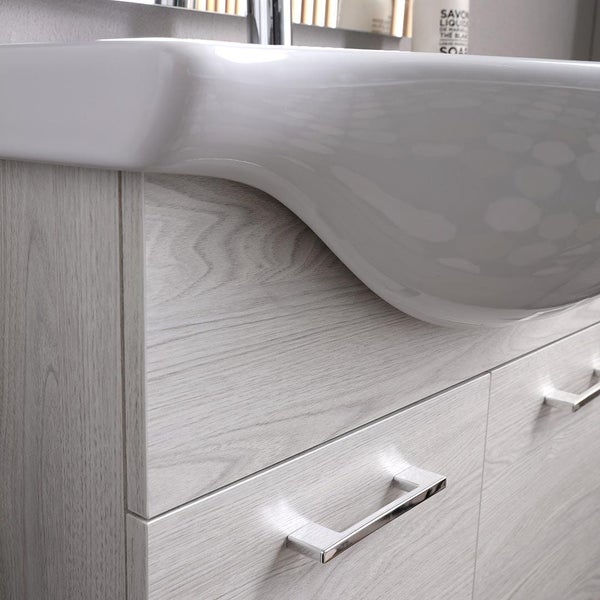 Waschtischunterschrank fürs Bad mit Holzmaserung, weißem Keramik-Waschbecken und verchromten Griffen.