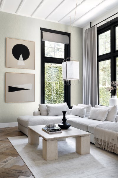 Wohnzimmer mit Sofa, Couchtisch, Fenster und Wandbildern für eine helle und organisierte Atmosphäre.