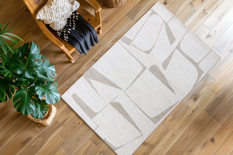 Rechteckiger Teppich mit abstraktem geometrischem Muster auf einem Holzboden in einem modern eingerichteten Wohnbereich.