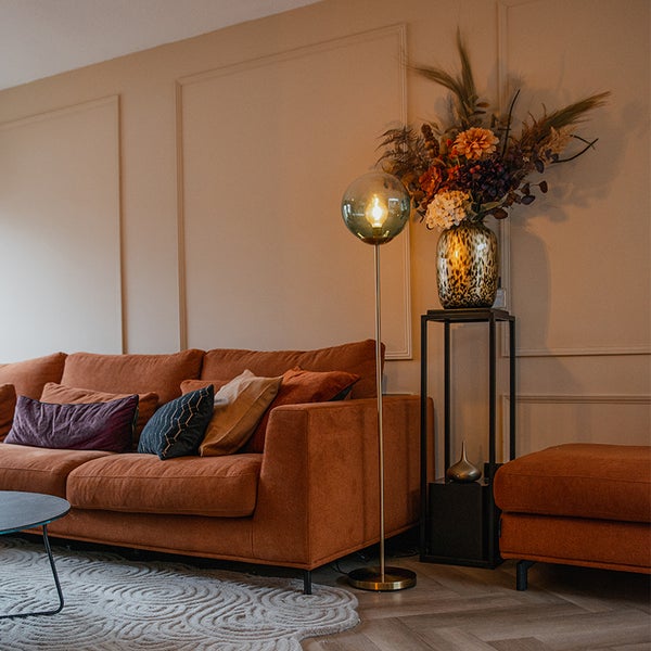 Wohnzimmer mit Sofa, Stehlampe und Blumenvase auf einem Beistelltisch