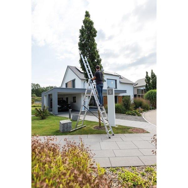 Mann auf einer Aluminium Mehrzweckleiter im Garten vor einem Haus.