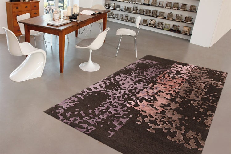 Moderner Wohnteppich mit abstraktem Muster im Essbereich mit Holztisch und Designstühlen auf glattem Boden.