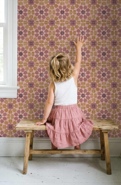 Geometrische Tapete mit Sternenmuster an einer Wand, vor der ein Kind auf einer Holzbank sitzt und die Wand berührt.