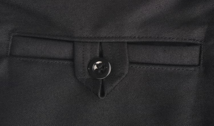 Detailansicht einer Gesäßtasche mit Knopfverschluss an einer schwarzen Arbeitshose aus robustem Gewebe.