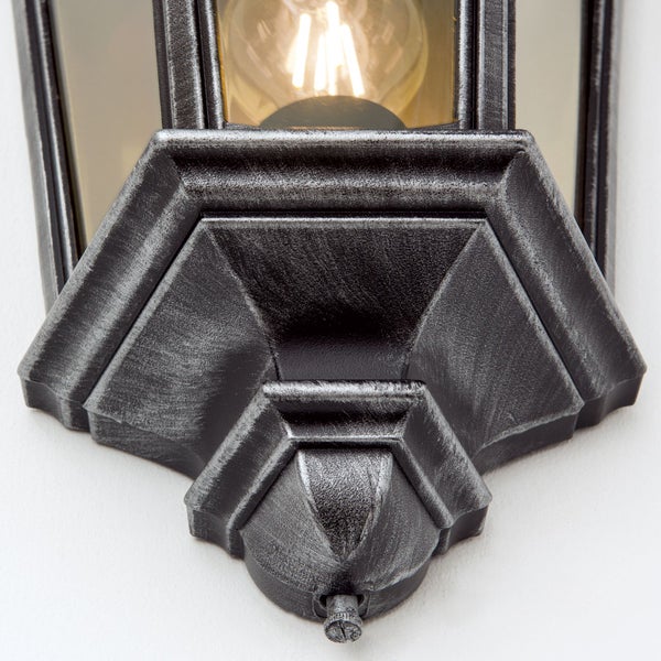 Detailansicht einer Außenwandleuchte im Laternen-Stil mit antik-silberner Oberfläche, Glaseinsätzen und sichtbarem Leuchtmittel.