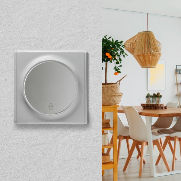 Ein Unterputz Rolladen-Drehschalter mit Pfeilsymbolen an der Wand, neben einem modern eingerichteten Esszimmer mit Holzmöbeln.