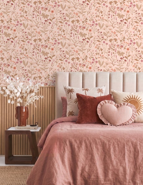 Schlafzimmer mit floraler Vliestapete, Bett mit verschiedenen Kissen und Wand mit Holzpaneelen.