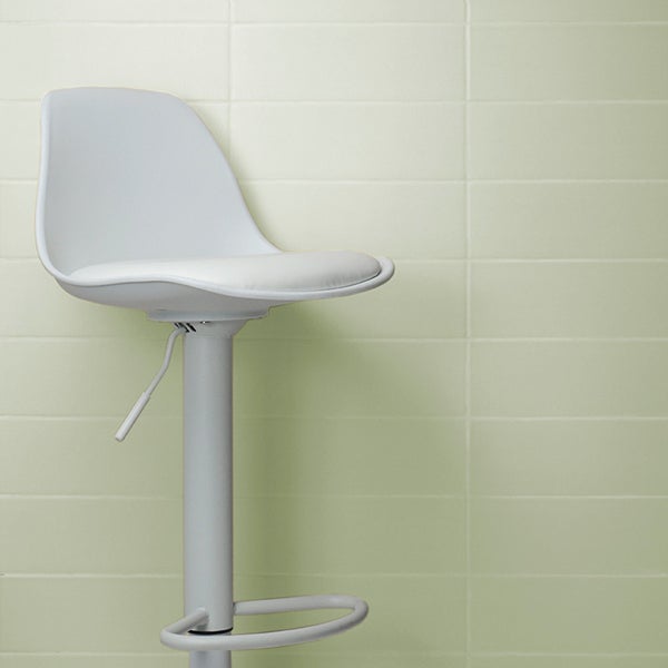 Moderner Barhocker mit Sitzschale und Gasdruckfeder vor einer gefliesten Wand