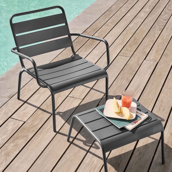 Gartenstuhl und Beistelltisch aus grauem Metall mit Lattenstruktur auf einer Holzterrasse neben einem Pool.