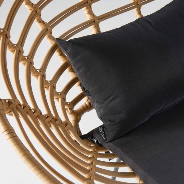 Nahaufnahme eines Hängesessels aus natürlichem Rattan mit einem schwarzen Stoffkissen.