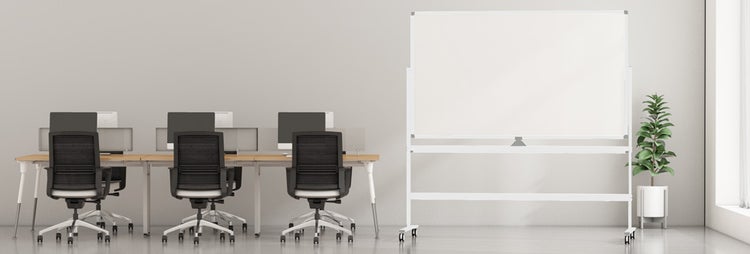 Modernes Büro mit drei Schreibtischen, schwarzen Bürostühlen, Computermonitoren und einem großen mobilen Whiteboard auf Rollen.