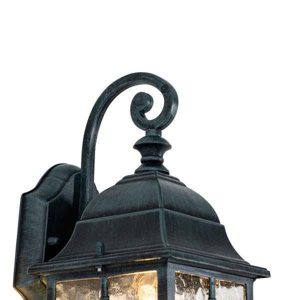 Nahaufnahme einer klassischen Außenwandleuchte im Laternenstil aus Metall mit dekorativem Schnörkel und strukturiertem Glas.