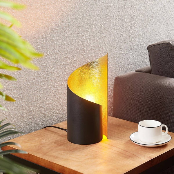 Dekorative Tischleuchte mit goldfarbener Innenseite auf einem Holztisch