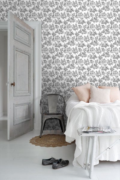 Vliestapete mit feinem Landschaftsmuster im Toile de Jouy Stil in einem hellen Schlafzimmer mit Metallstuhl und weißem Bett.