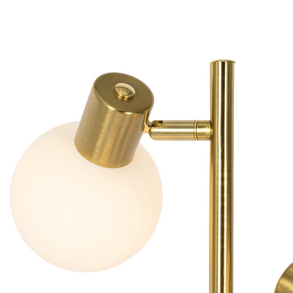 Detailaufnahme einer goldenen Stehlampe mit kugelförmigem Lampenschirm