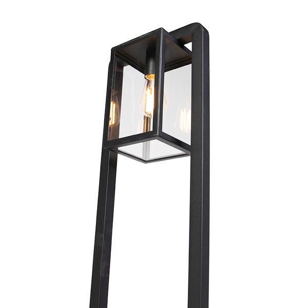 Moderne schwarze Außenstandleuchte mit rechteckigem Metallrahmen, Glaseinsätzen und sichtbarem, leuchtendem Leuchtmittel.