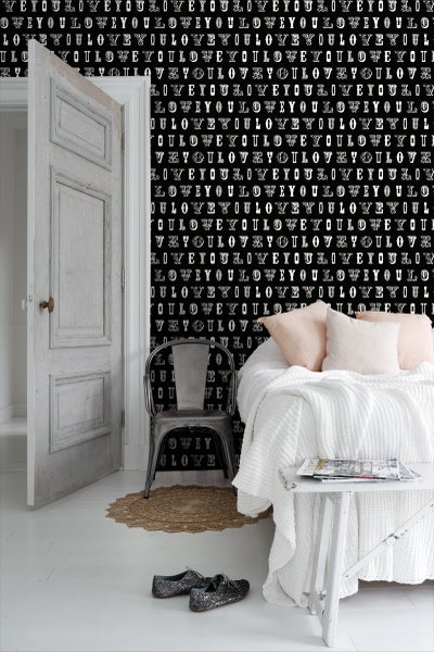 Schlafzimmer mit Bett, Stuhl und Tapete mit Schriftzug