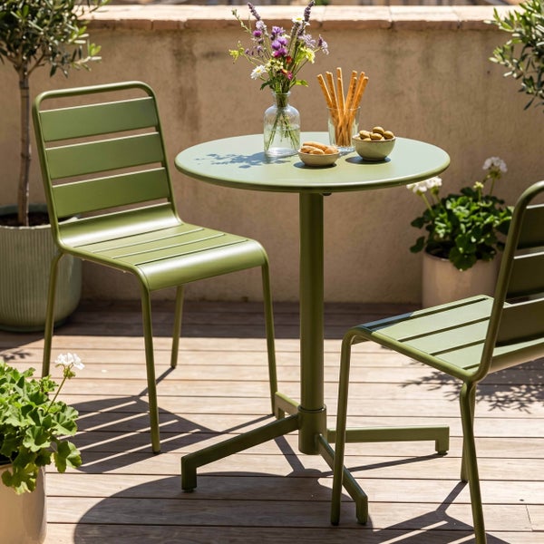Modernes Bistro-Set aus einem runden Metalltisch und zwei Metallstühlen auf einer hellen, organisierten Holzterrasse mit Blumendekoration.