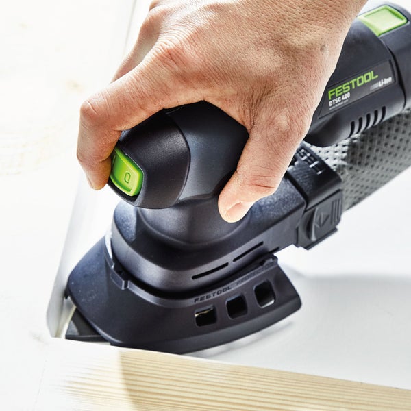 Eine Hand bedient einen Festool DTSC 400 Akku-Dreieckschleifer auf einem Werkstück.