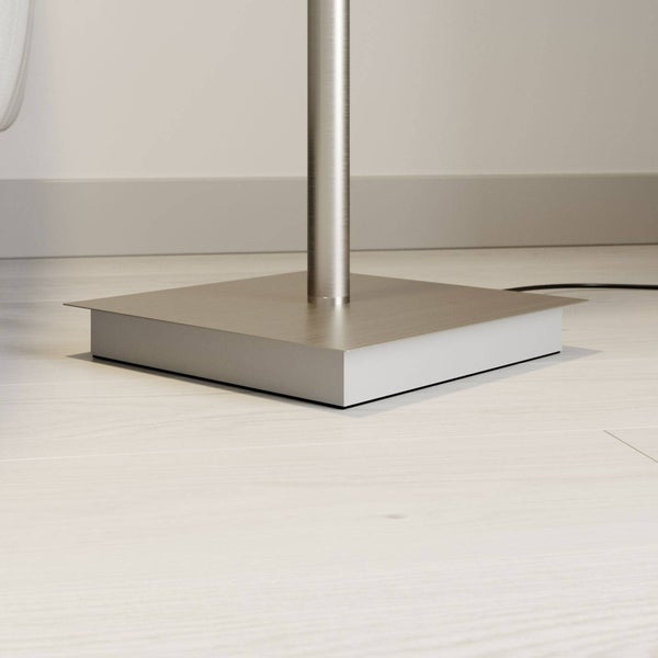 Quadratischer Lampenfuß einer Stehleuchte aus gebürstetem Metall mit zylindrischer Stange auf hellem Boden.